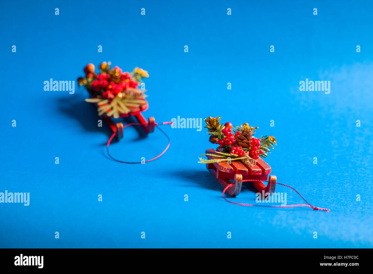 Christmas card in horizontal orientation with decorative sleds standing on blue background. Stock Photo