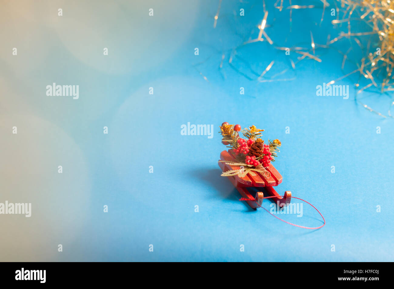 Christmas card with decorative sled standing on blue background in blurred glow balls. Stock Photo