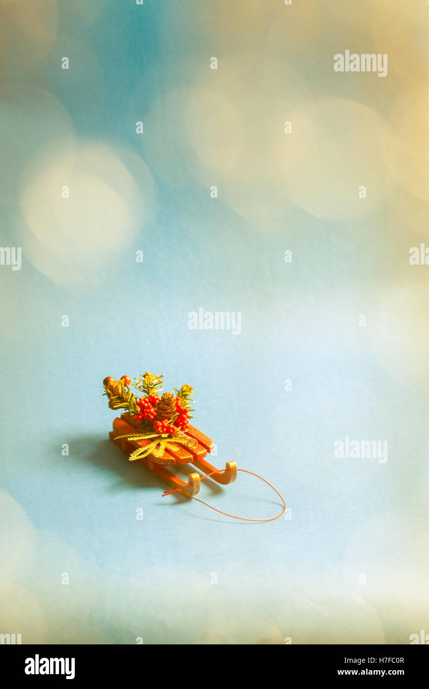 Christmas card with decorative sled standing on blue background in blurred glow balls. Stock Photo