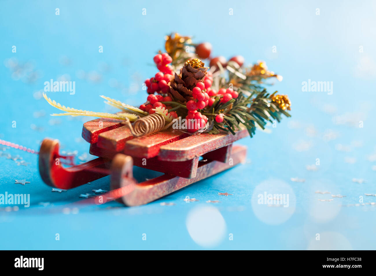 Christmas card with shine silver star and decorative sled standing on blue background in blurred glow balls. Stock Photo