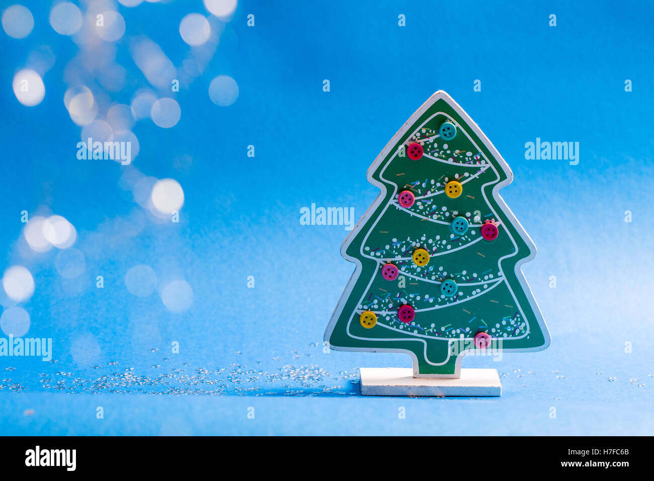 Wooden figurine of christmas tree with glued coloured buttons and glow stars and balls. Stock Photo