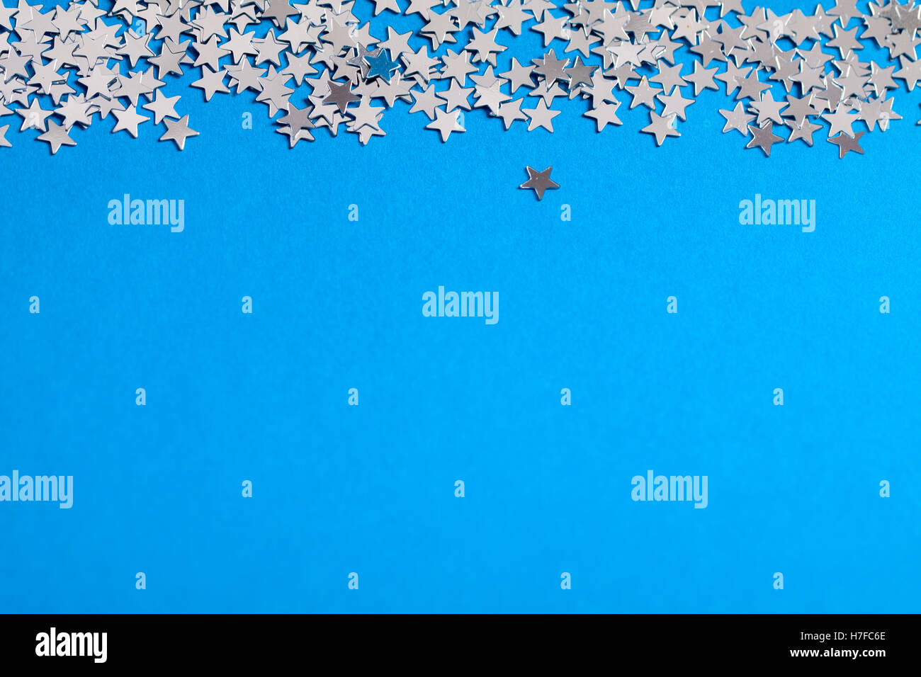 Frame of scatters little silver stars on blue background. Stock Photo