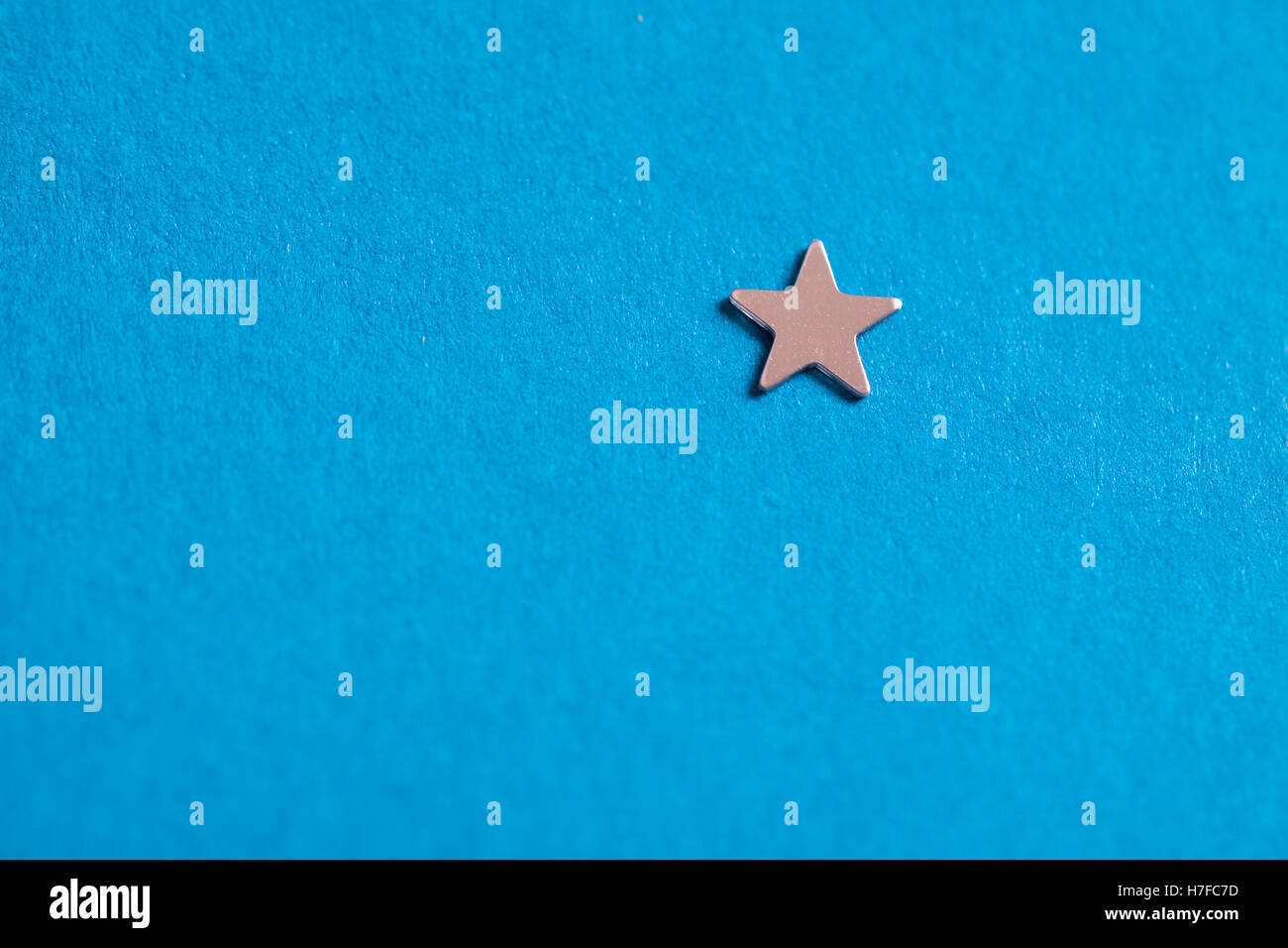 Little silver shiny star on blue background. Stock Photo