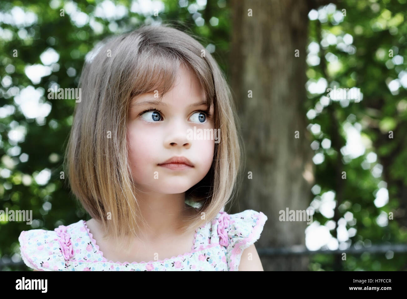 Cute little girl with bobbed hair cut looking away from camera. Extreme shallow depth of field. Stock Photo