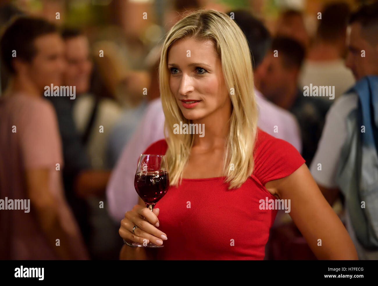 Frustrated woman with wine glass, group of men behind, Germany Stock Photo