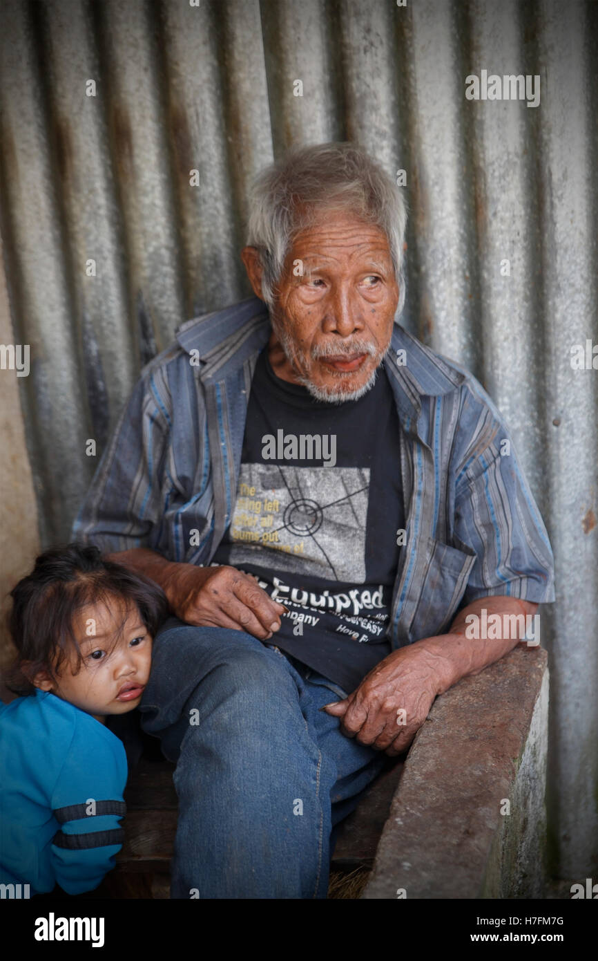 BANAUE,PHILIPPINES-OCTOBER 06,2016: Grandfather takes care of her granddaughter while her parents work in the nearby rice fields Stock Photo