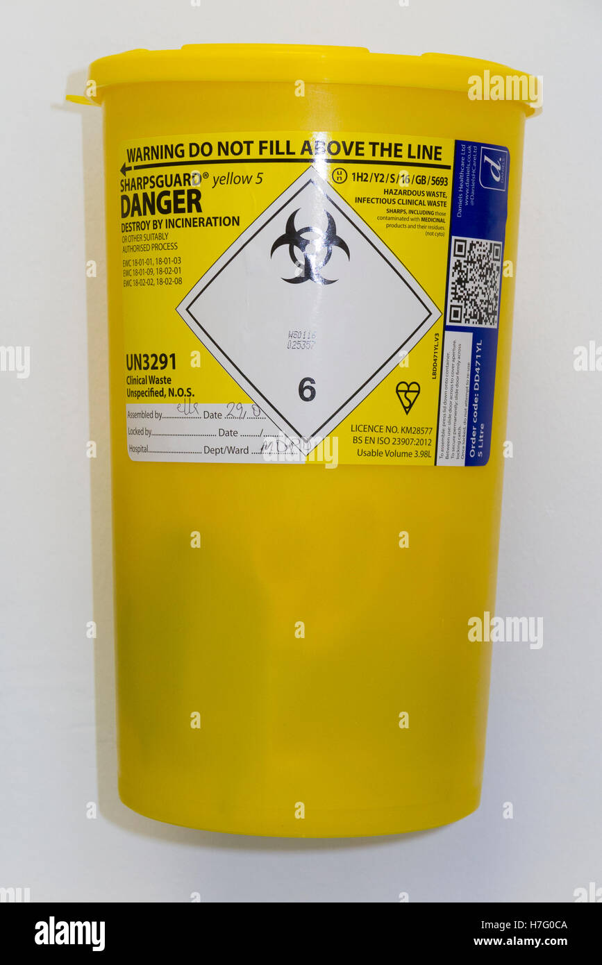 Hospital type sharp waste bin on the wall of a clinic, for the safe disposal of medical sharps paraphernalia. Stock Photo