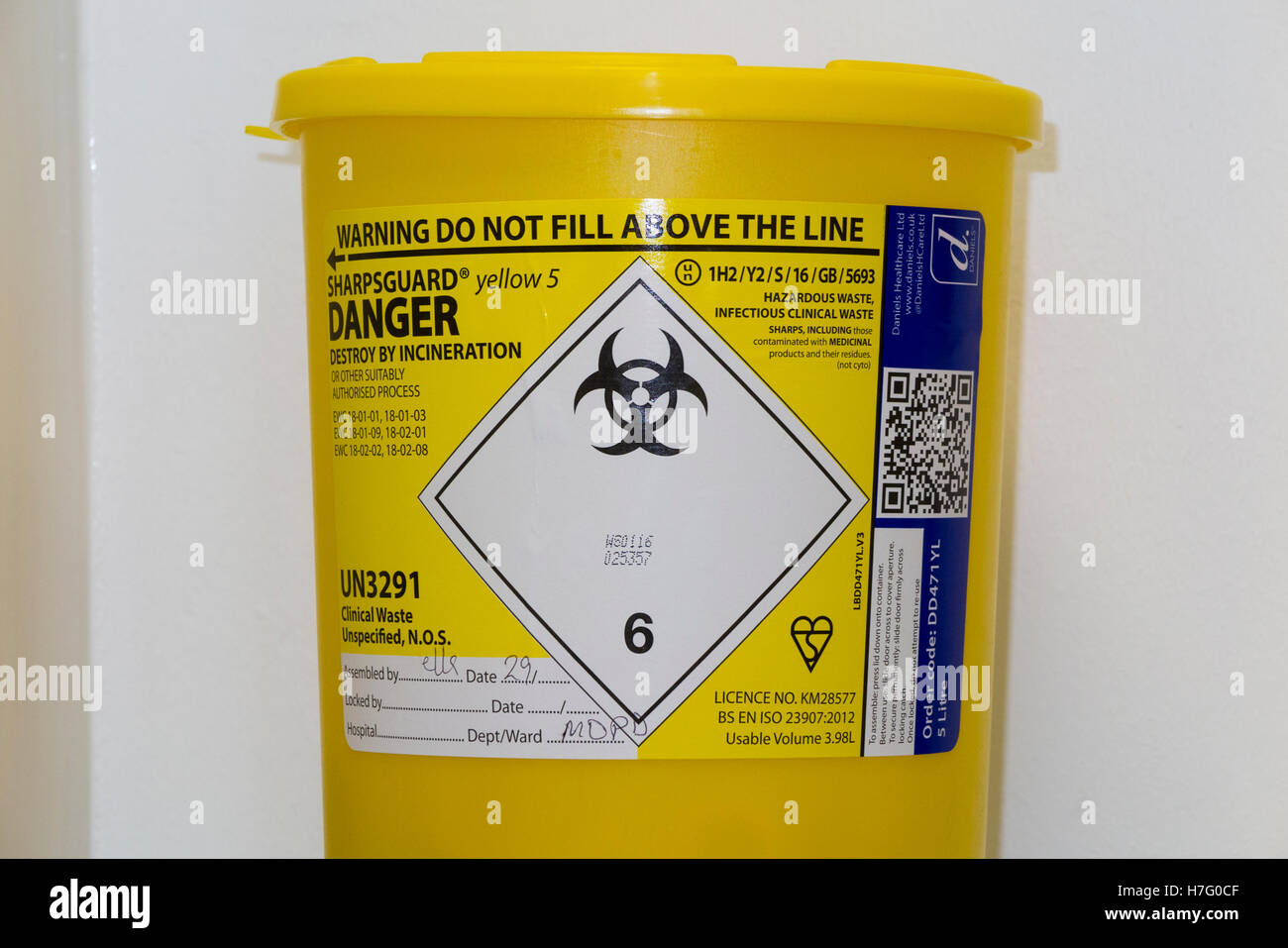 Hospital type sharp waste bin on the wall of a clinic, for the safe disposal of medical sharps paraphernalia. Stock Photo