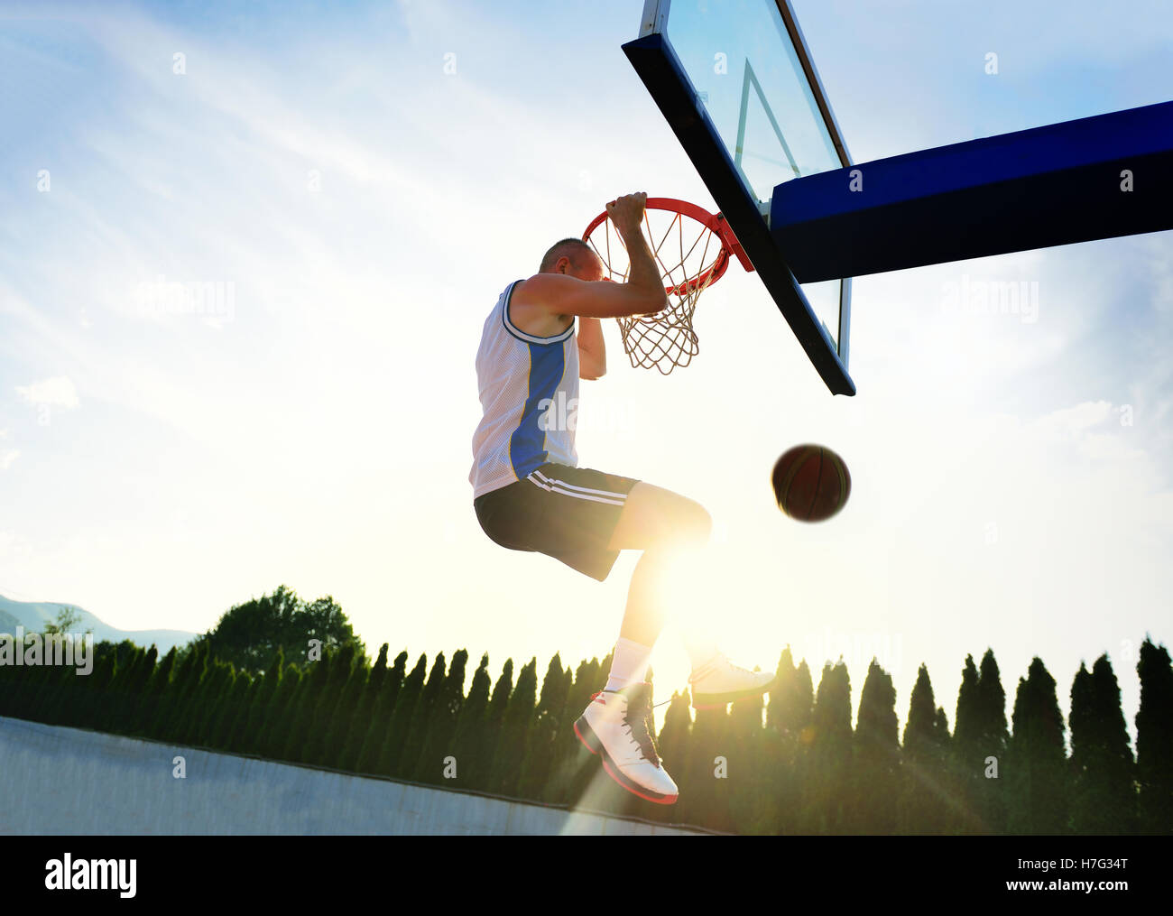 Young basketball player drives to the hoop for a high flying slam dunk Stock Photo