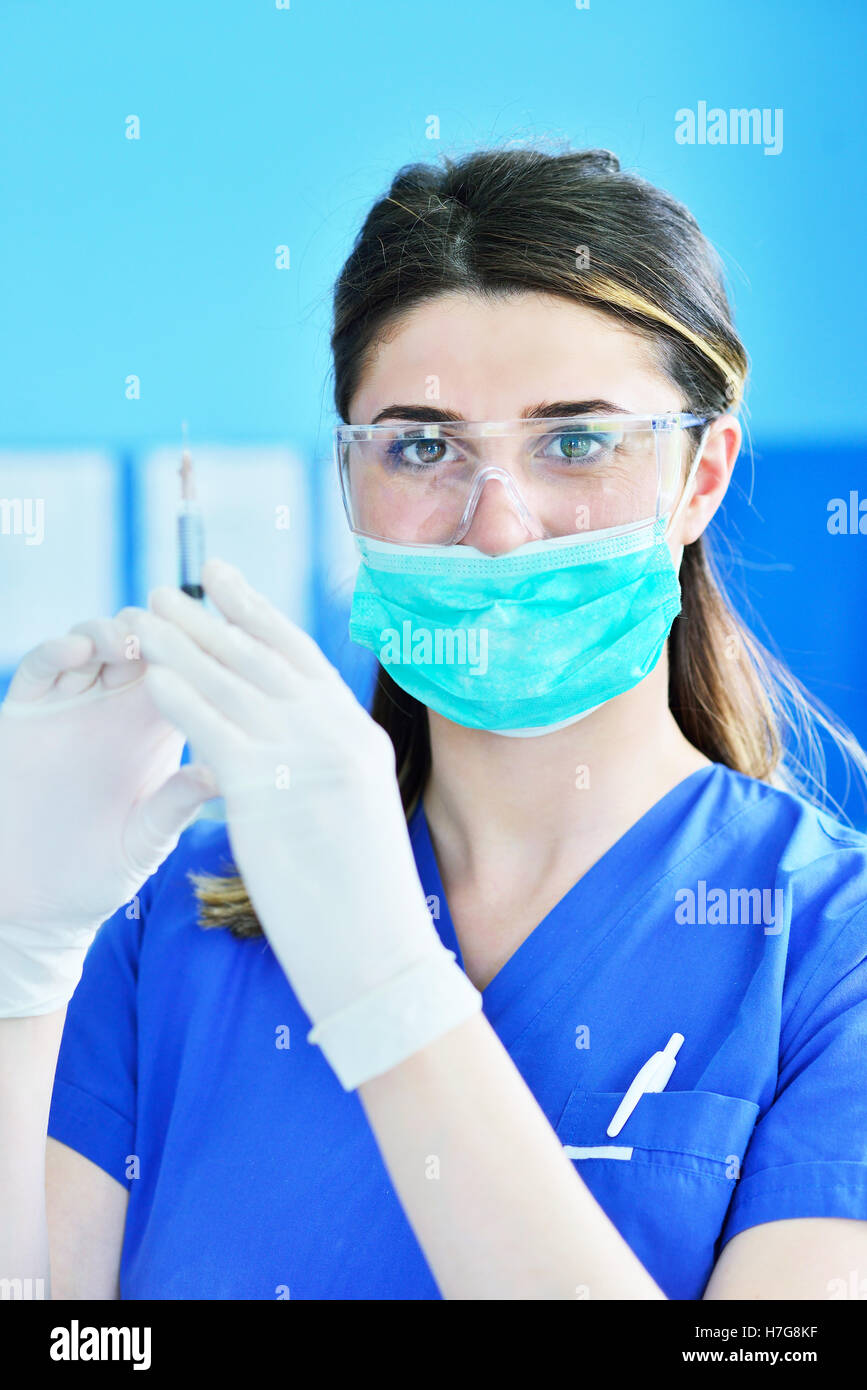 The surgeon dentist in mask holding syringe for injecting anesthesia