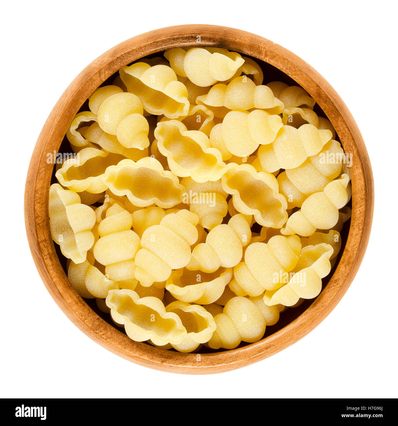 Gnocchi pasta in wooden bowl. Decorative short-cut lobed shells of Italian noodles. Uncooked dried durum wheat semolina pasta. Stock Photo