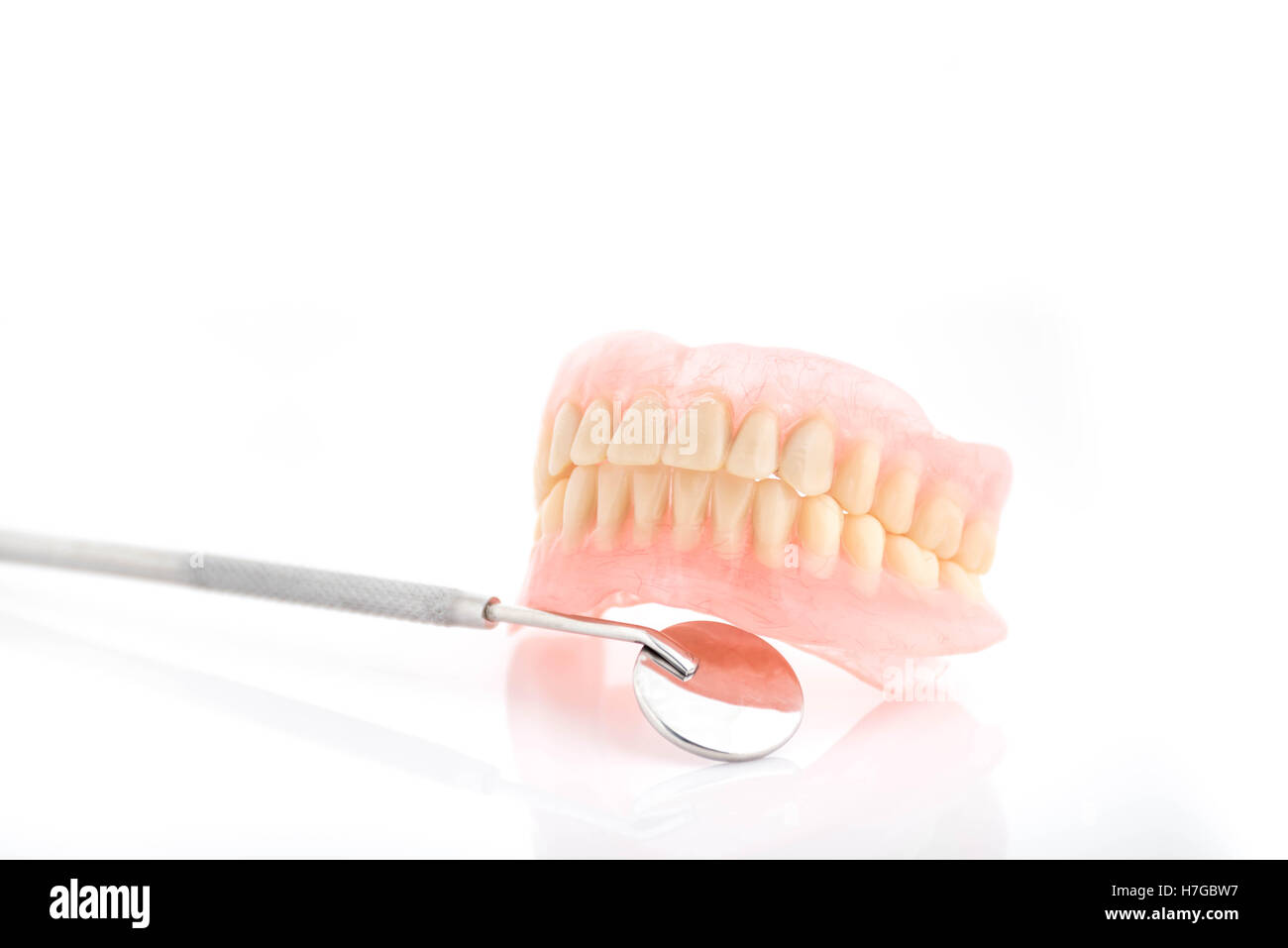 Tatar on dentures and dental mirror pn white background Stock Photo