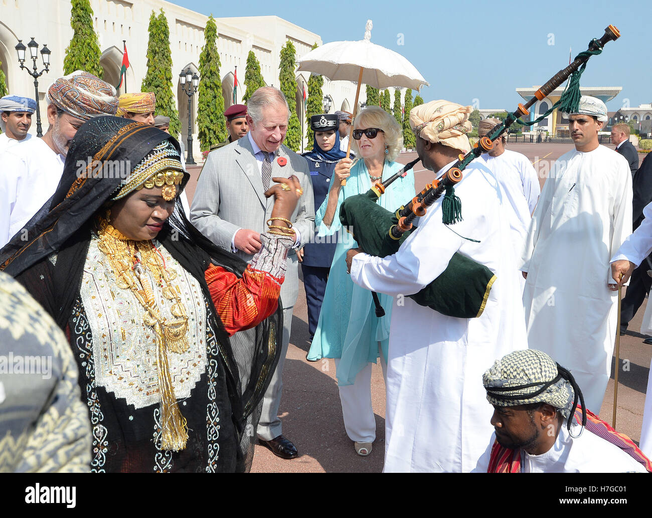 The Prince of Wales and the Duchess of Cornwall watch a man playing the bagpipes during a cultural welcome to Muscat, the capital of Oman, at the start of their official tour of the Middle East. Stock Photo