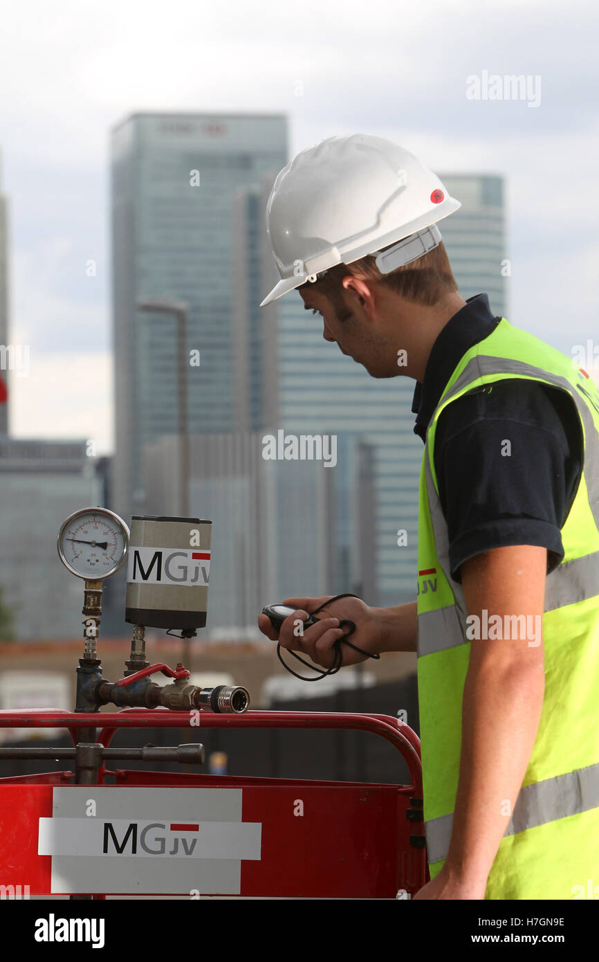 waste water worker checking valves with London skyline in background Stock Photo