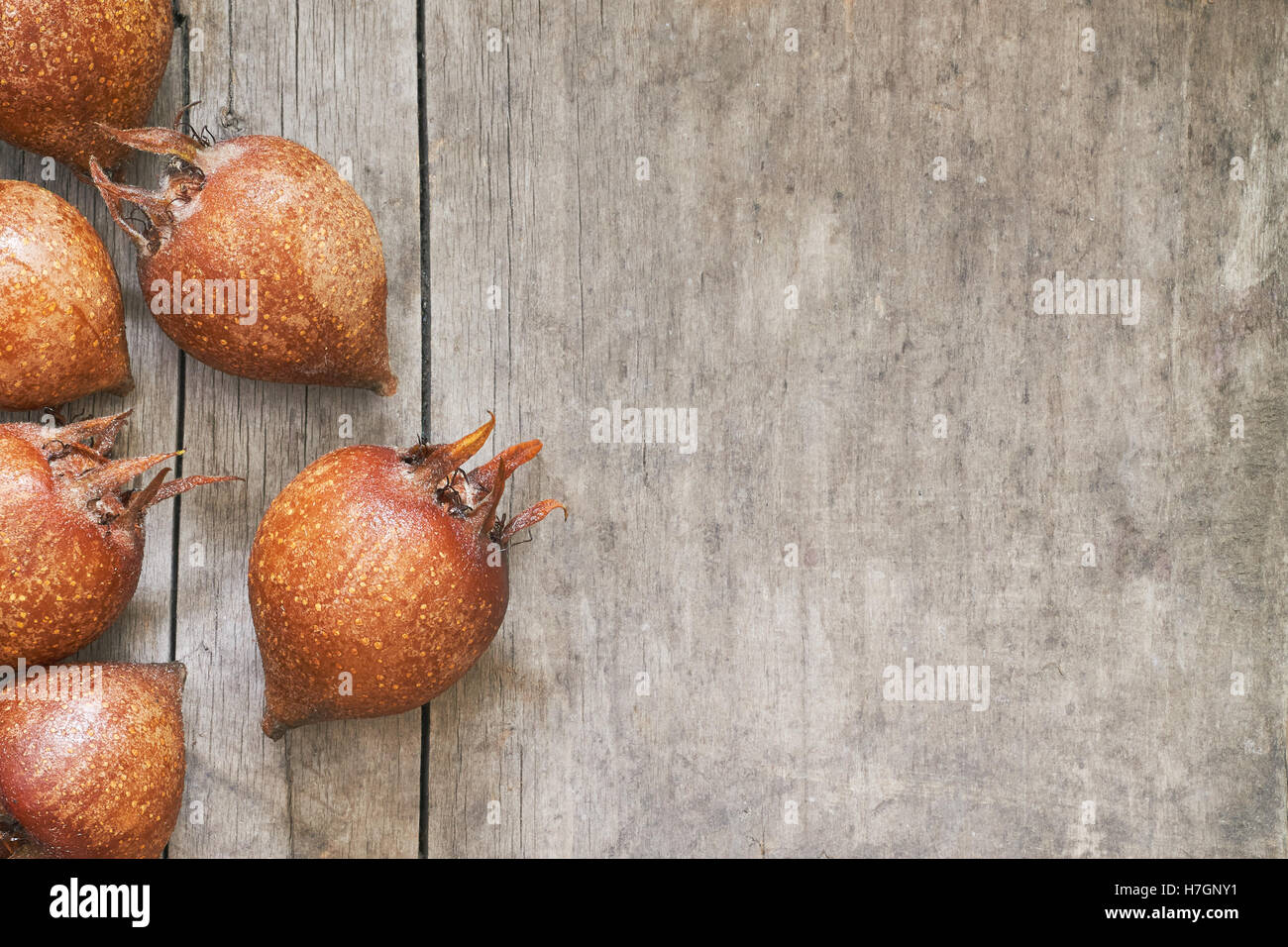 Common medlar fruit (mispel) on grey rustic wooden background. Top view with plenty of copy space Stock Photo