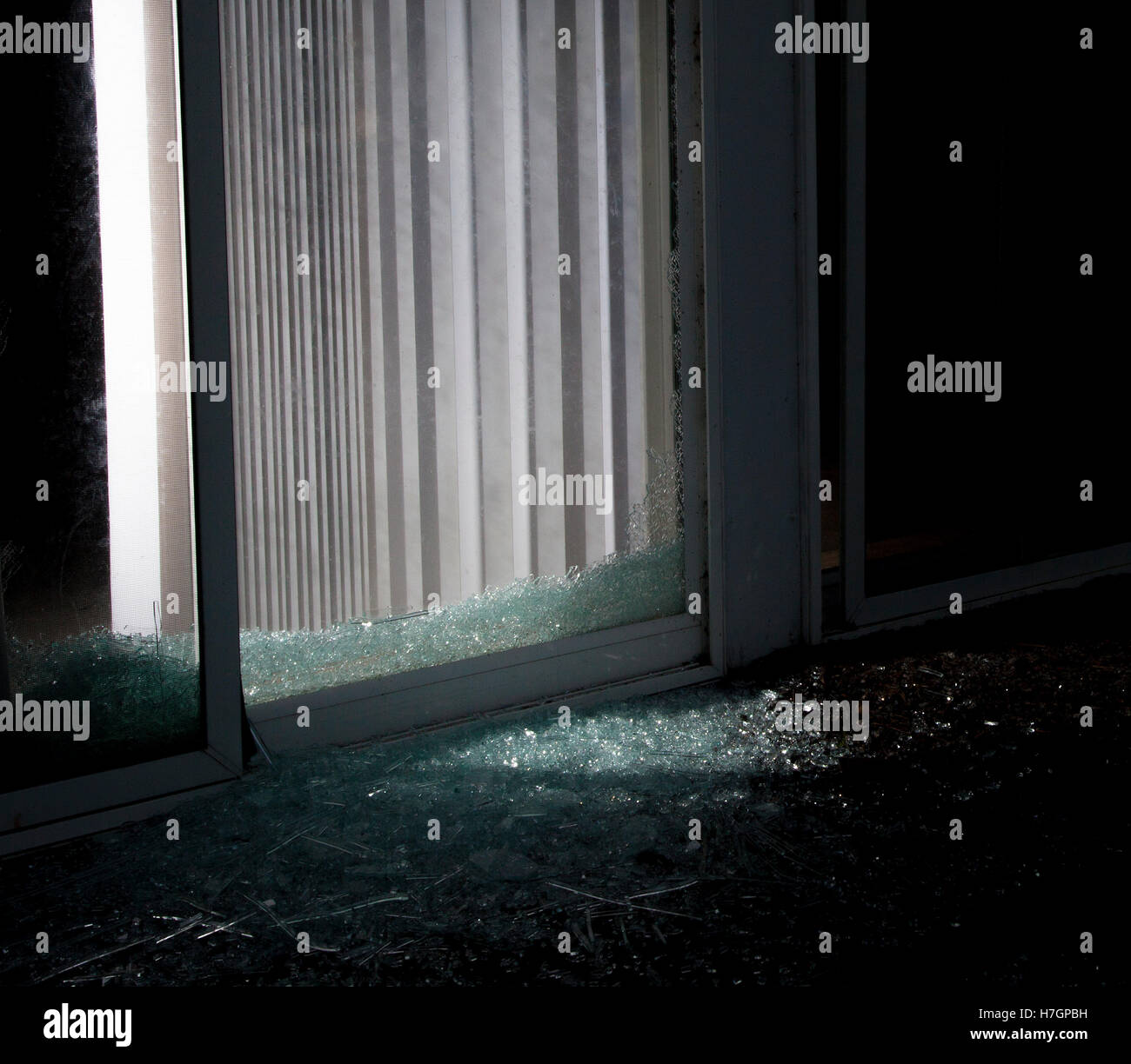 Light coming from inside a shattered sliding glass door that could be the burglar Stock Photo