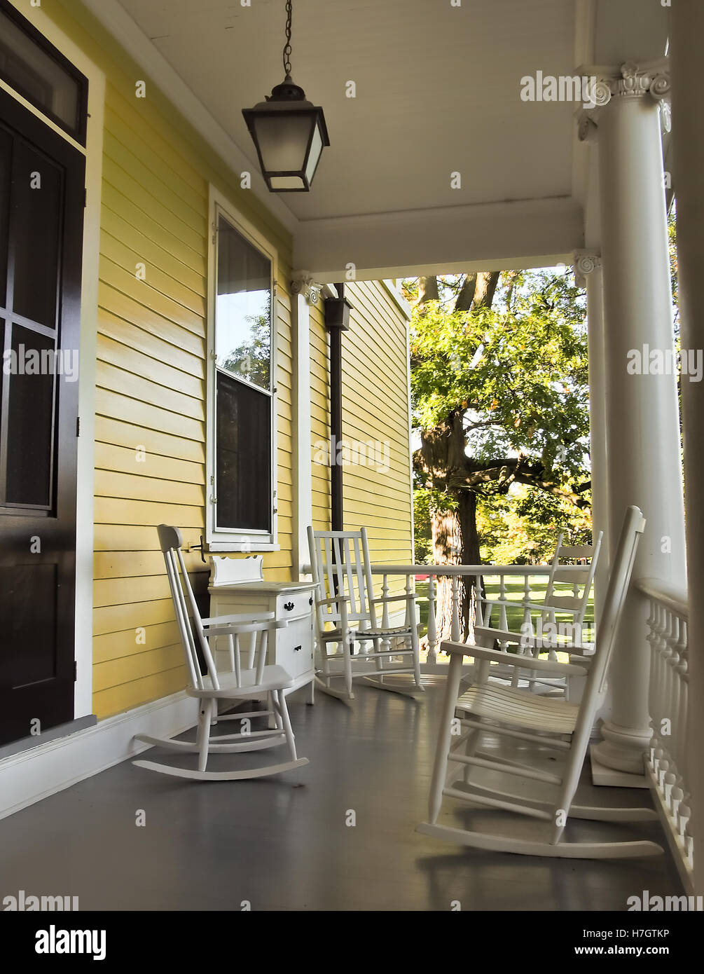 yellow country porch with wicker rocking chairs Stock Photo