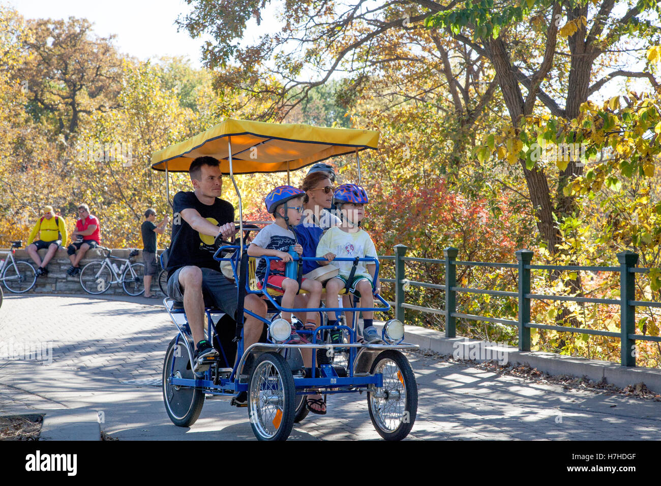 Dad and mom peddling their two children in a canopy covered Double Surrey bike at Minnehaha Park. Minneapolis Minnesota MN USA Stock Photo
