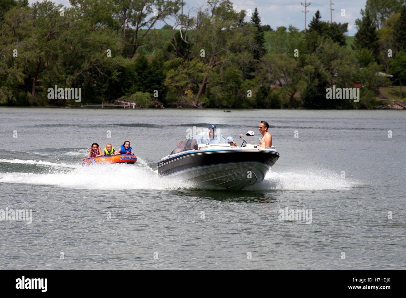 Parents pulling their kids on a water tube with speed boat on a lake. Clitherall Minnesota MN USA Stock Photo