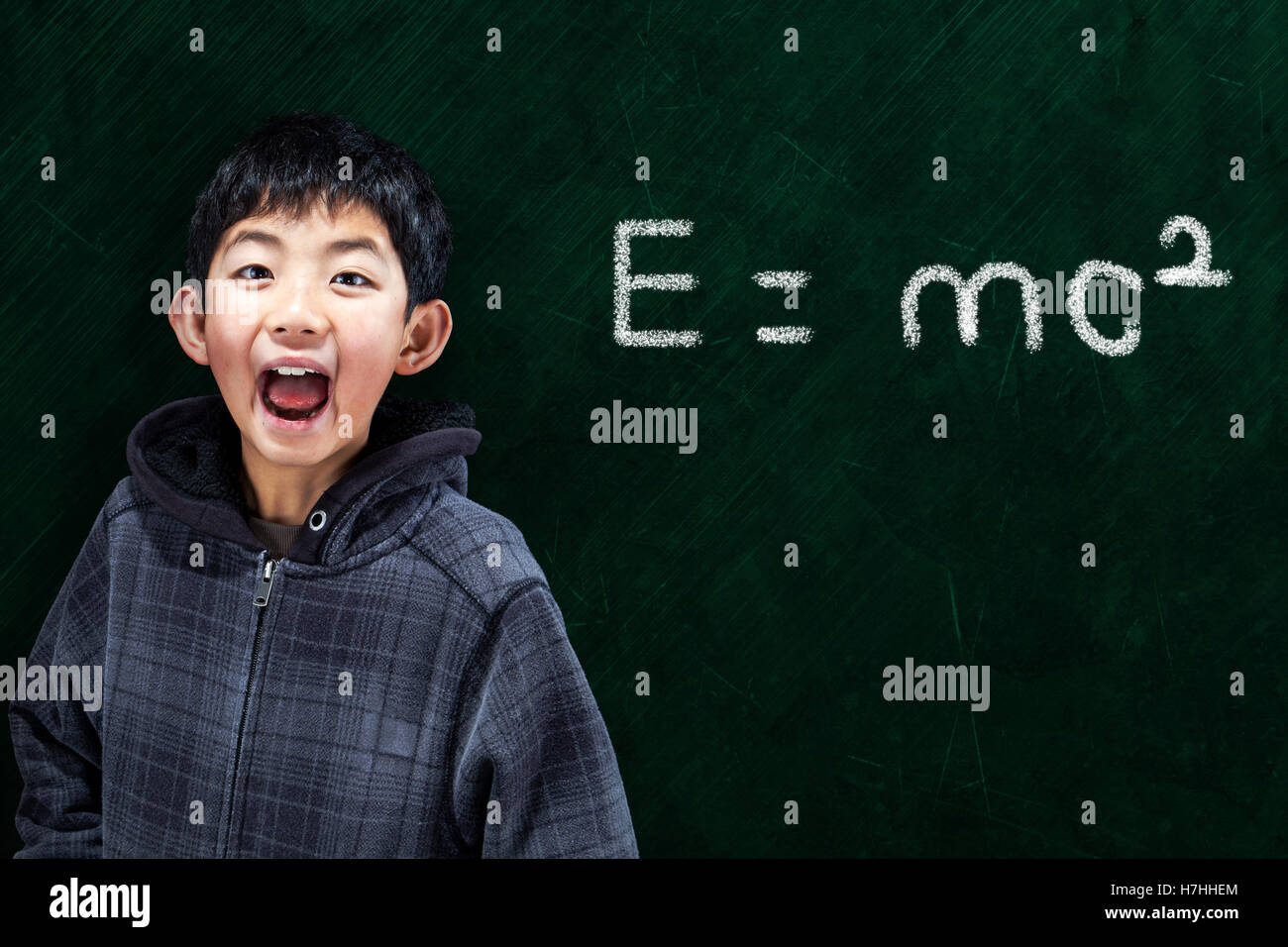 Smart Asian boy with in classroom setting with Math equation on chalkboard background and copy space Stock Photo