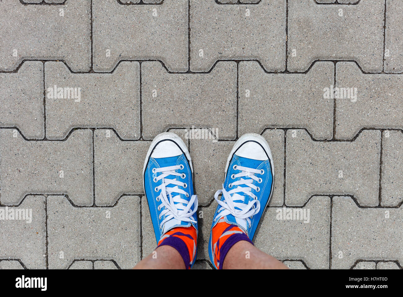 On a walk - wearing sneakers, top view on concrete pavement and blue shoes Stock Photo