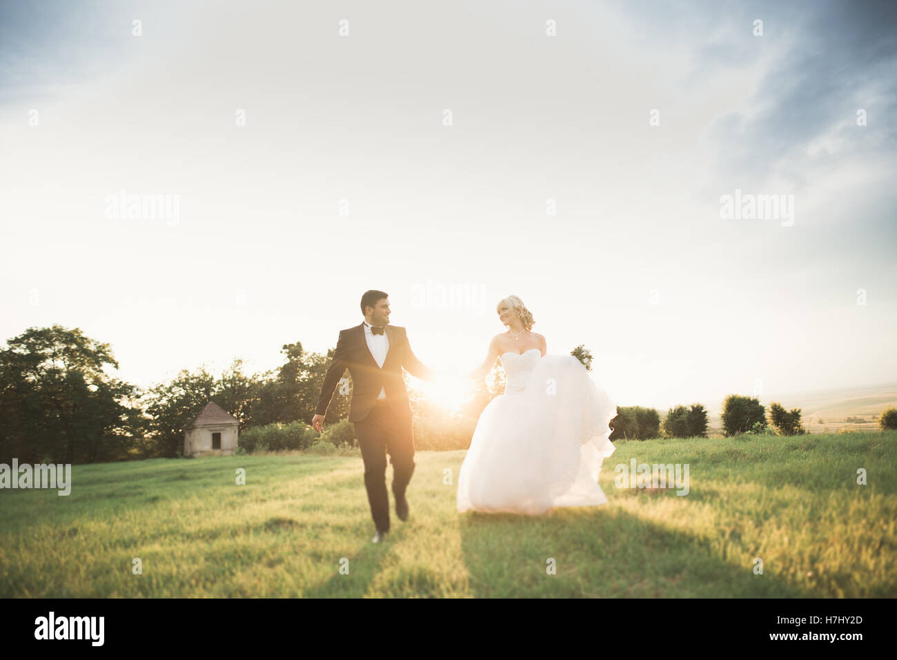 Stylish couple of happy newlyweds walking in the park on their wedding ...