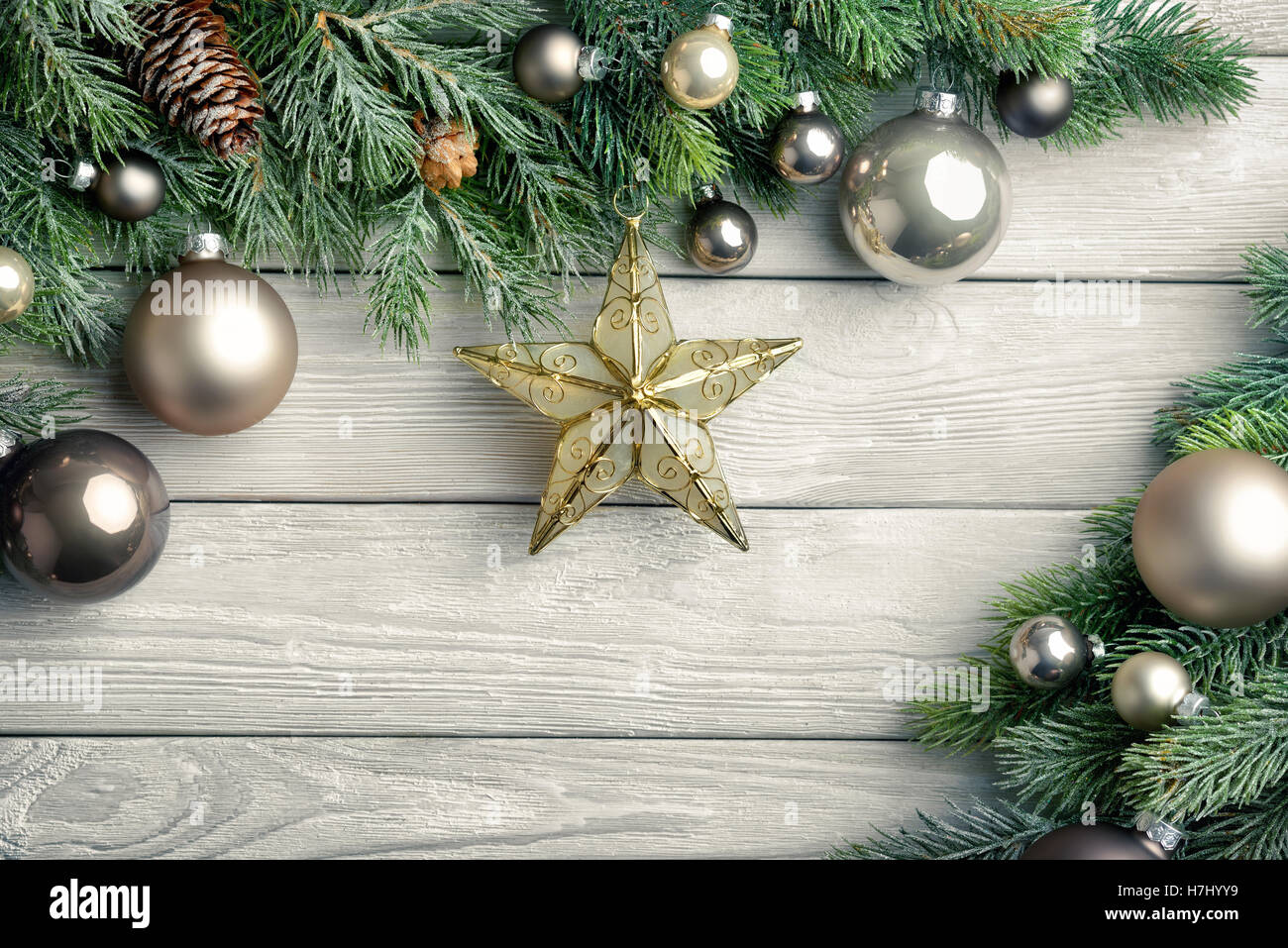 Christmas background with bright wooden board and fir branches decorated with silver baubles and a gold star - modern, simple an Stock Photo