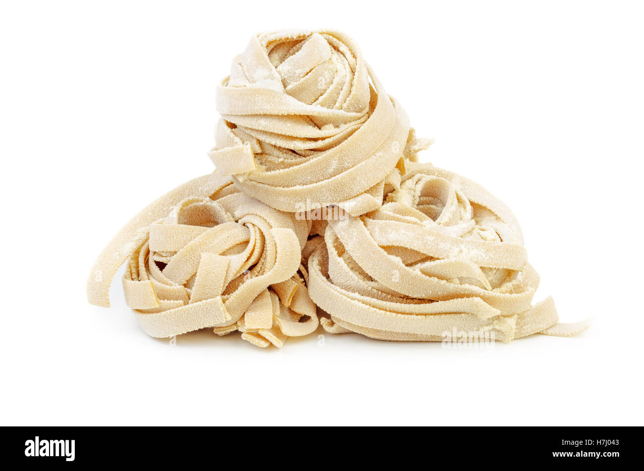Pile of uncooked homemade rolled traditional italian pasta. Portion of raw fettuccine or tagliatelle or pappardelle. Dry pasta Stock Photo