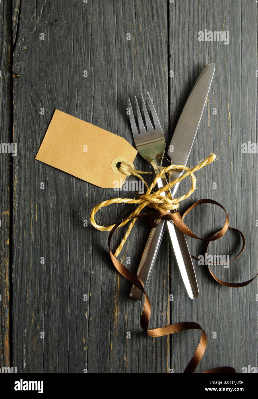 Fork and knife tied together on a wooden table background with tag Stock Photo Alamy