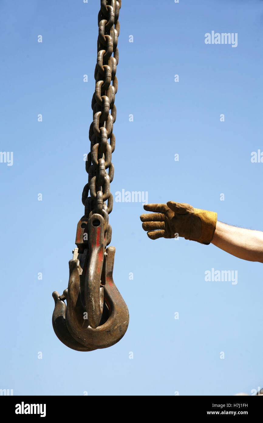 Long chains with hooks hanging vertically against blue sky Stock Photo