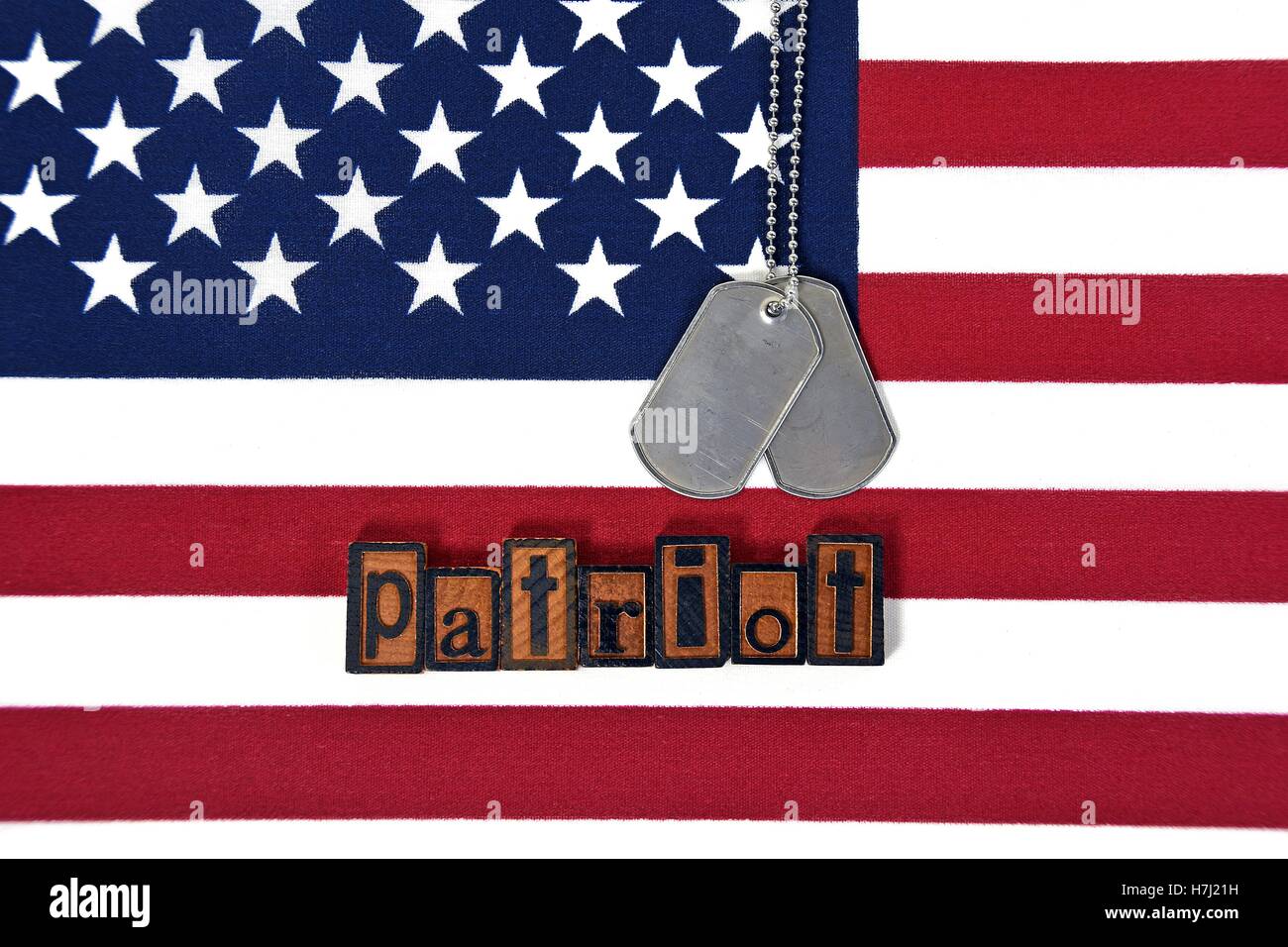 word patriotic in wooden letterpress type with dog tags on American flag Stock Photo