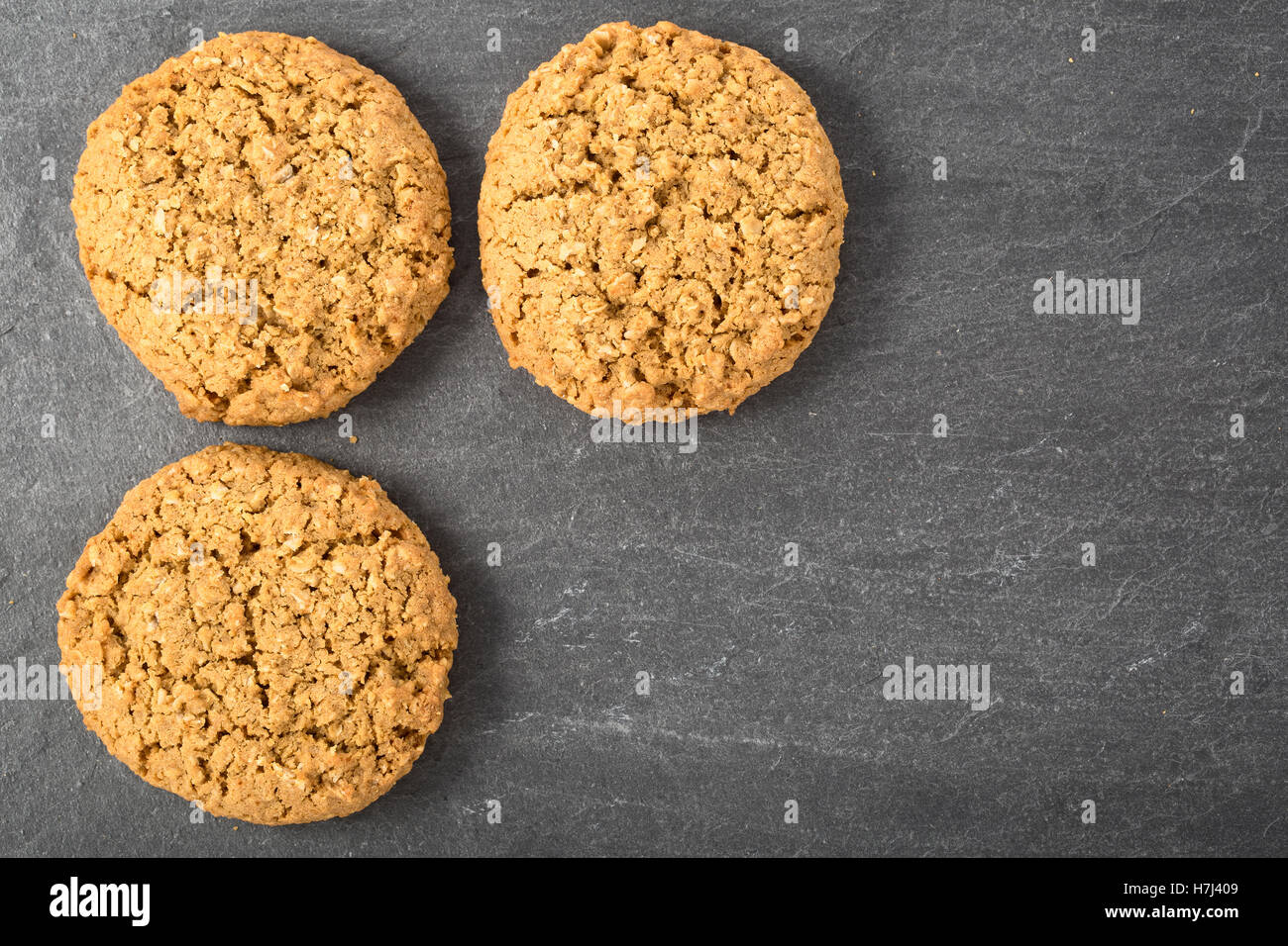 Three oatmeal cookies on a stone surface with copy space Stock Photo