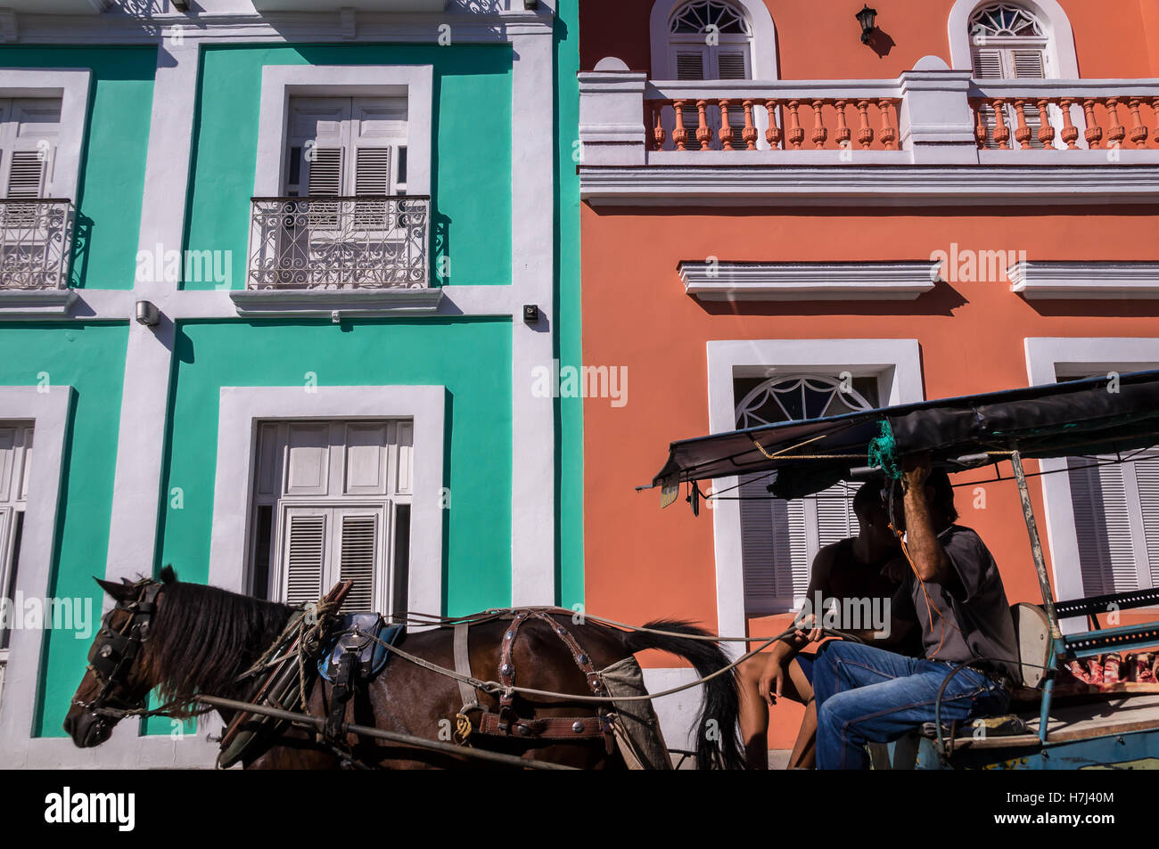 Horse pulling carriage in front of colorful colonial facade Stock Photo