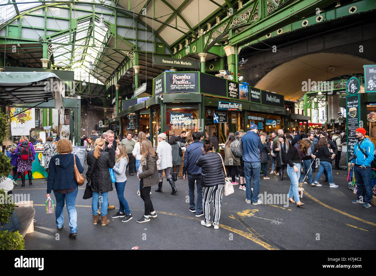 LONDON - OCTOBER 31, 2016: Visitors browse the specialty food stalls at Borough Market, one of the city's largest and oldest. Stock Photo