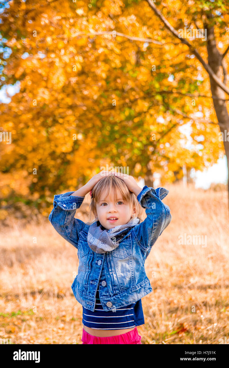 Little girl in the autumn golden park. Holding hands on the head Stock ...
