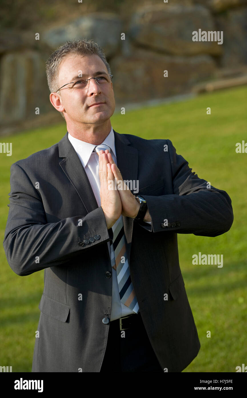 Businessman doing a relaxation exercise in a park Stock Photo