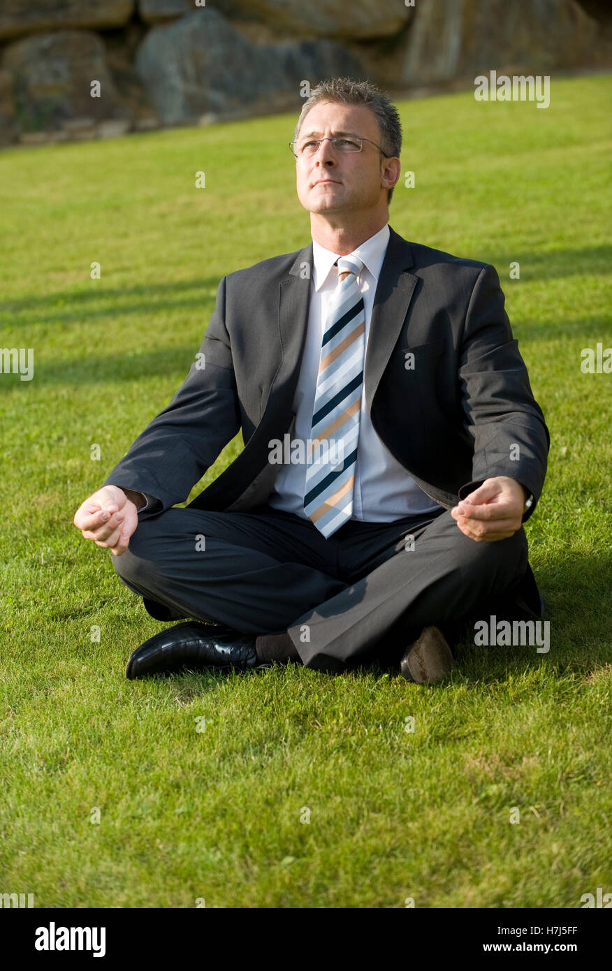 Businessman doing yoga in a park Stock Photo - Alamy