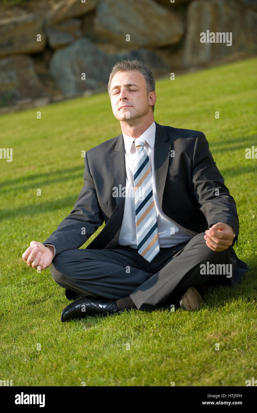 Businessman doing yoga in a park Stock Photo - Alamy