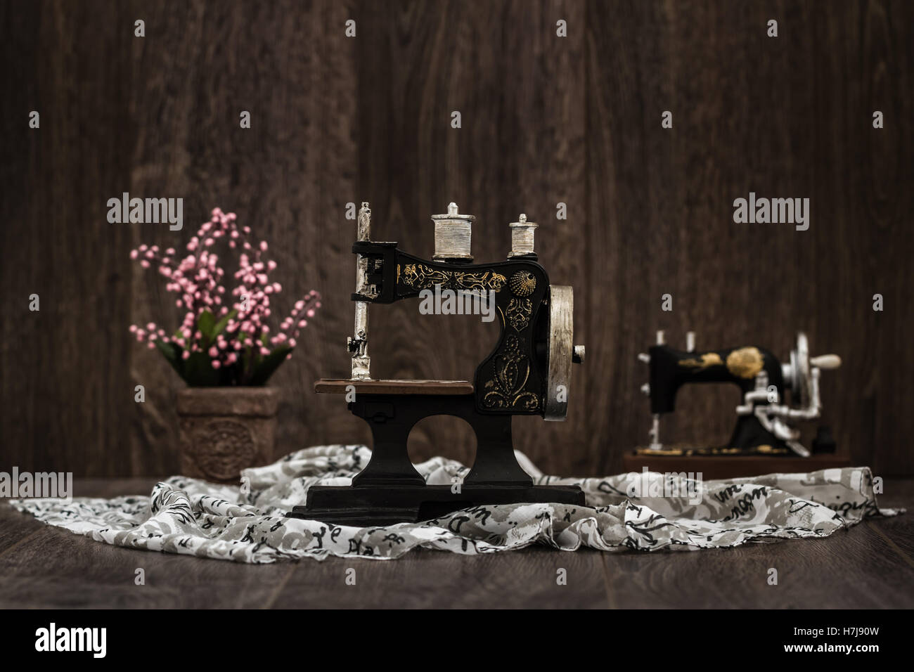 Small nostalgic decorative sewing machine on brown wooden background Stock Photo