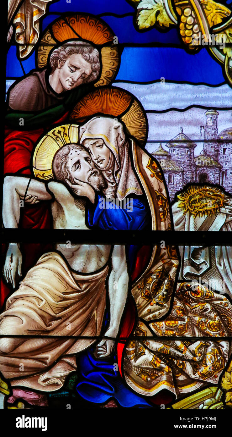 Stained Glass window, depicting Jesus taken from the Cross into Mother Mary's arms, in the Cathedral of Saint Rumboldt in Mechel Stock Photo