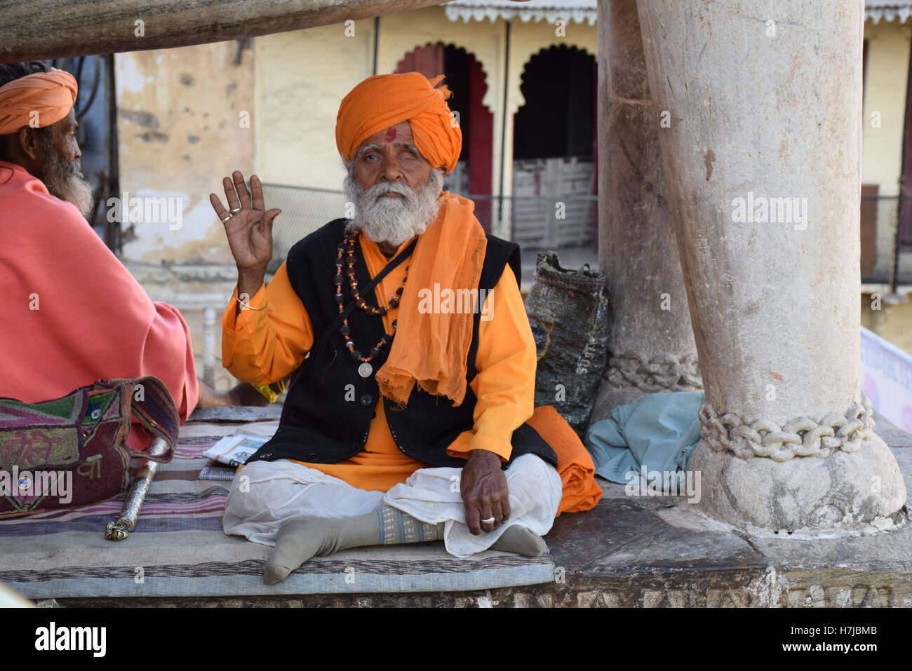 Indian man with beard and orange turban sitting outside a temple in Udaipur, Rajasthan, India Stock Photo