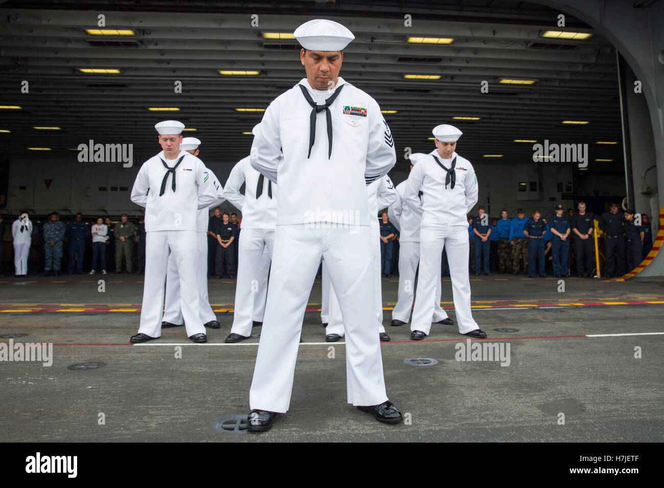 U.S. Navy sailors bow their heads in prayer during a burial at sea ceremony aboard the USN Wasp-class amphibious assault ship USS Kearsarge August 1, 2014. Stock Photo