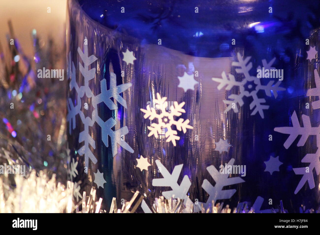 cobalt blue glass and snowflakes resting in silver garland with light reflecting off the silver garland,close up of light reflecting off cobalt glass Stock Photo