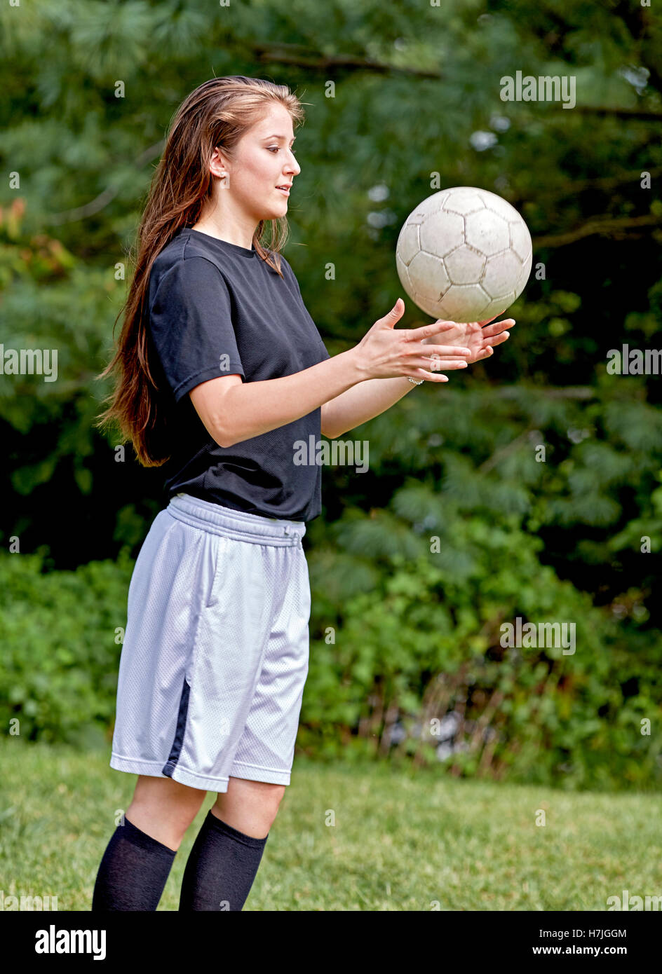 Young girl on the grass tossing a soccer ball and smiling Stock Photo