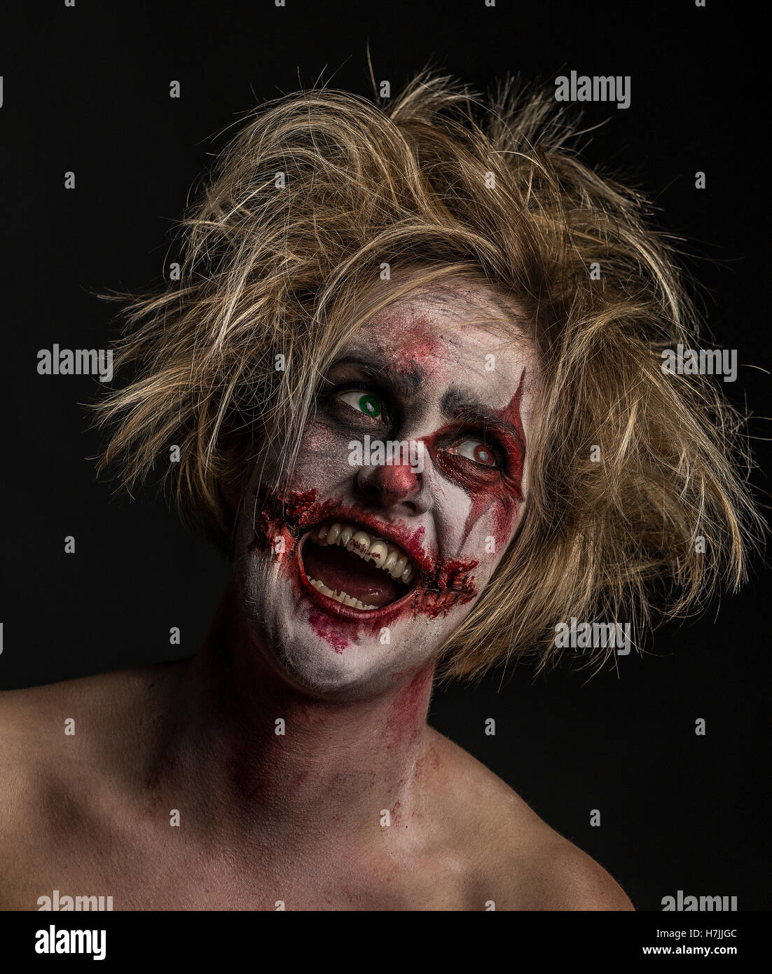 Blonde female model as bloodstained, crazed, insane, murderous, laughing clown Stock Photo