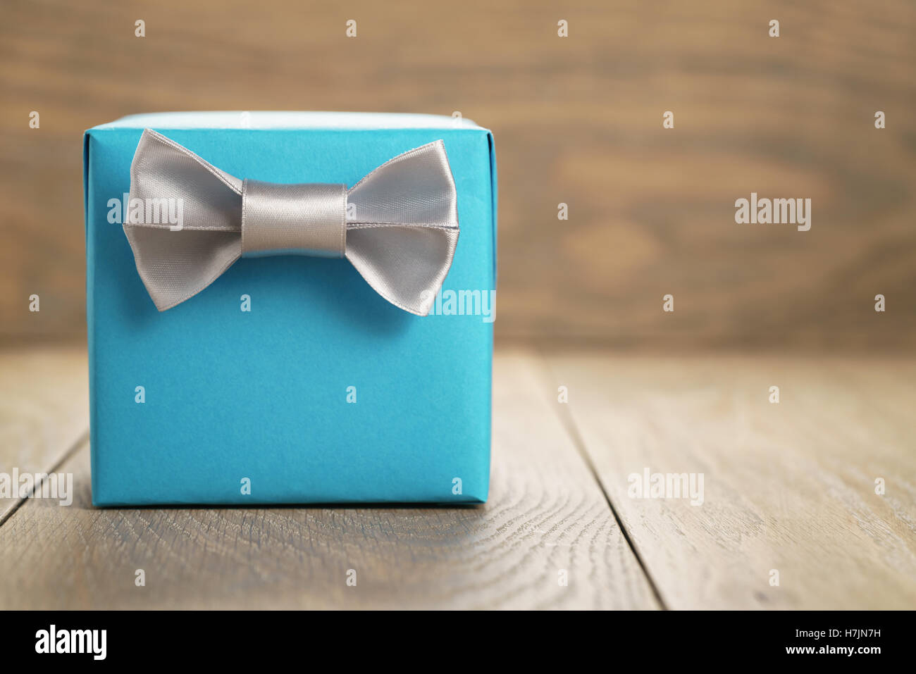light blue gift box with minimalistic silver ribbon bow on wooden Stock