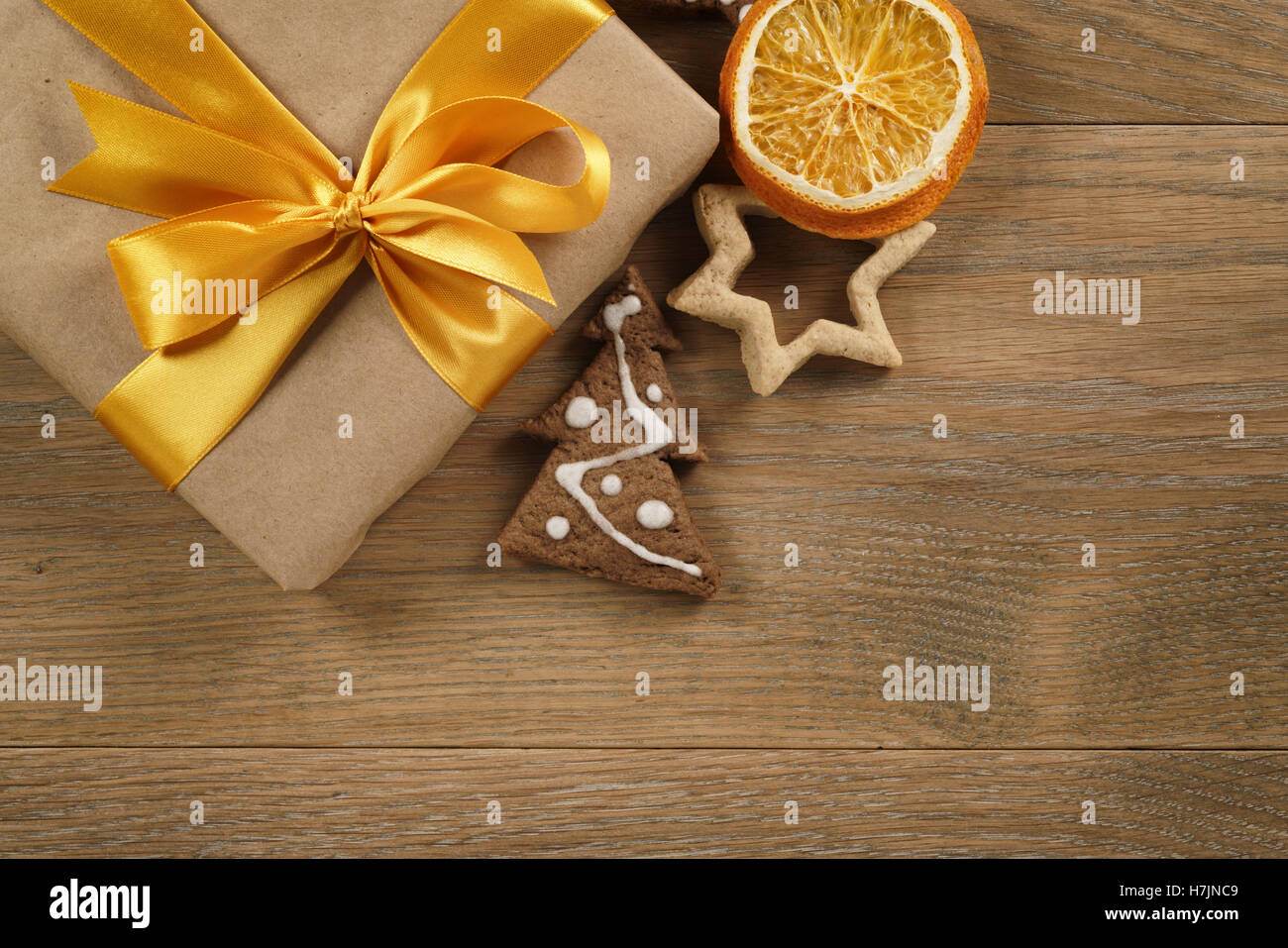 gift box with golden ribbon bow and christmas cookies on wood table Stock Photo