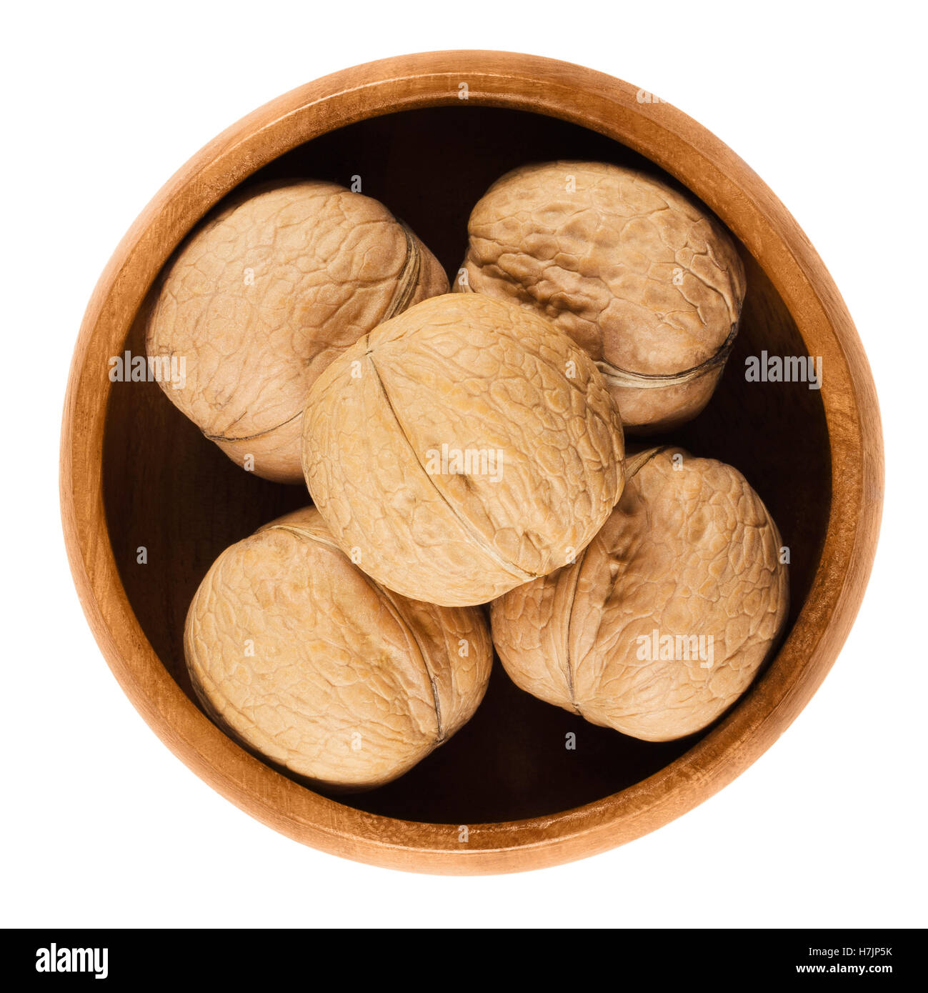 Whole walnuts with shells in a wooden bowl on white background. Brown dried nuts of common walnuts, Juglans regia. Stock Photo