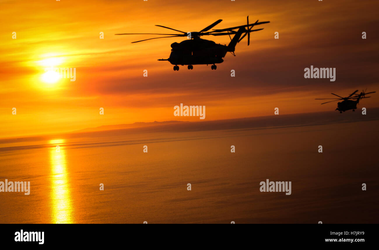 Two CH-53E Super Stallion helicopters fly over the ocean at sunset while returning to the Marine Corps Air Station Miramar May 15, 2014 in Miramar, California. Stock Photo