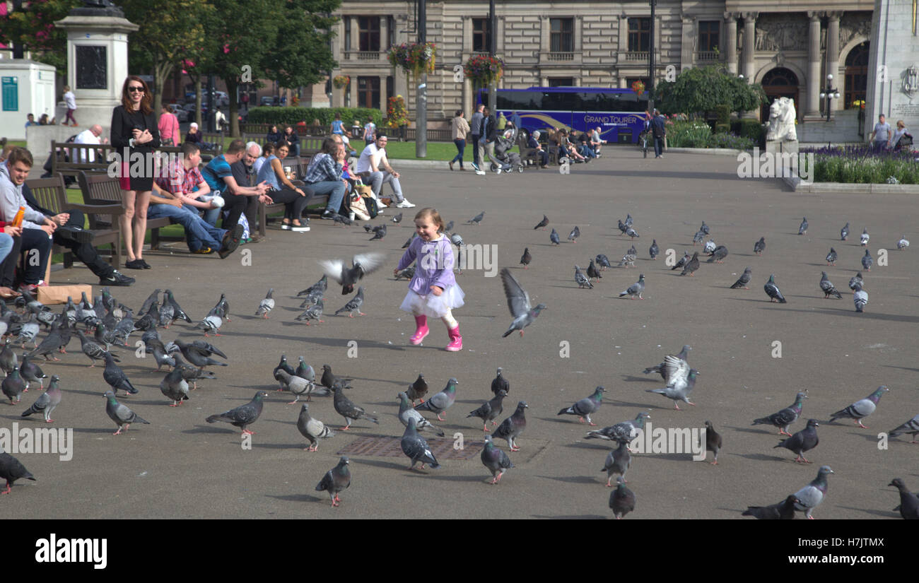 Tourists and locals enjoy little girl playing with pigeons in george square Stock Photo